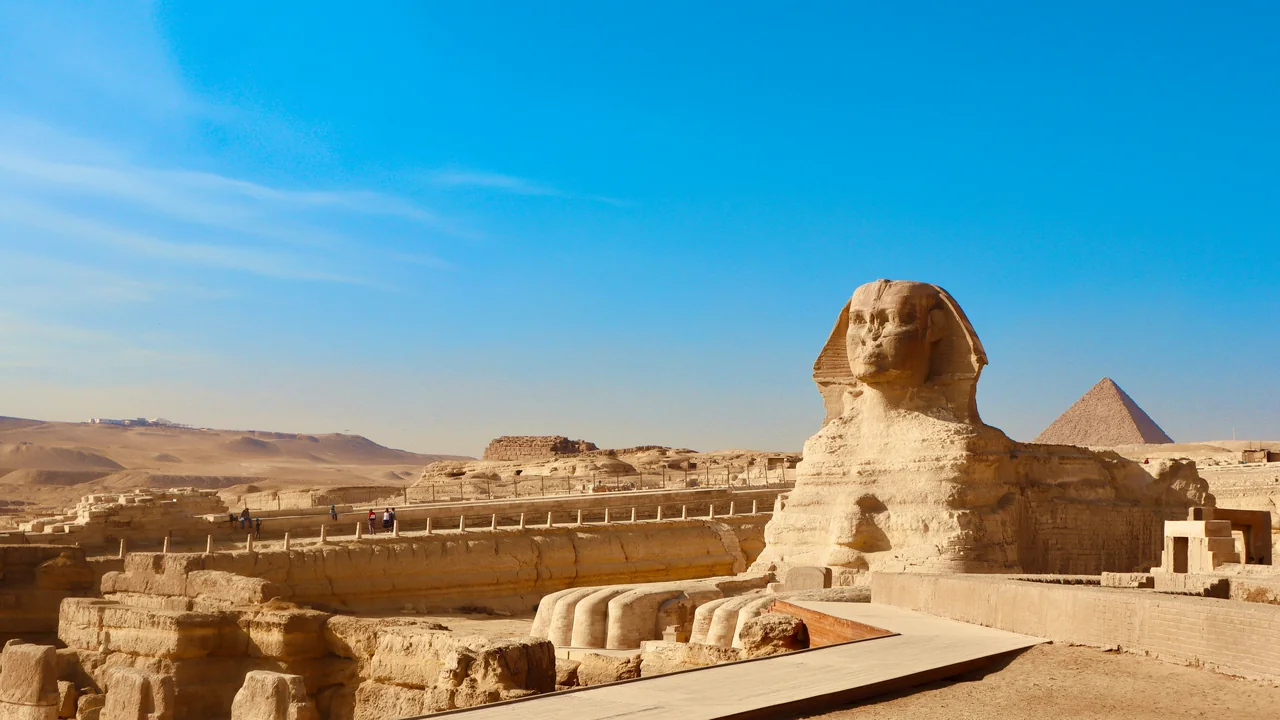 Die Große Sphinx von Gizeh, dahinter eine Pyramide