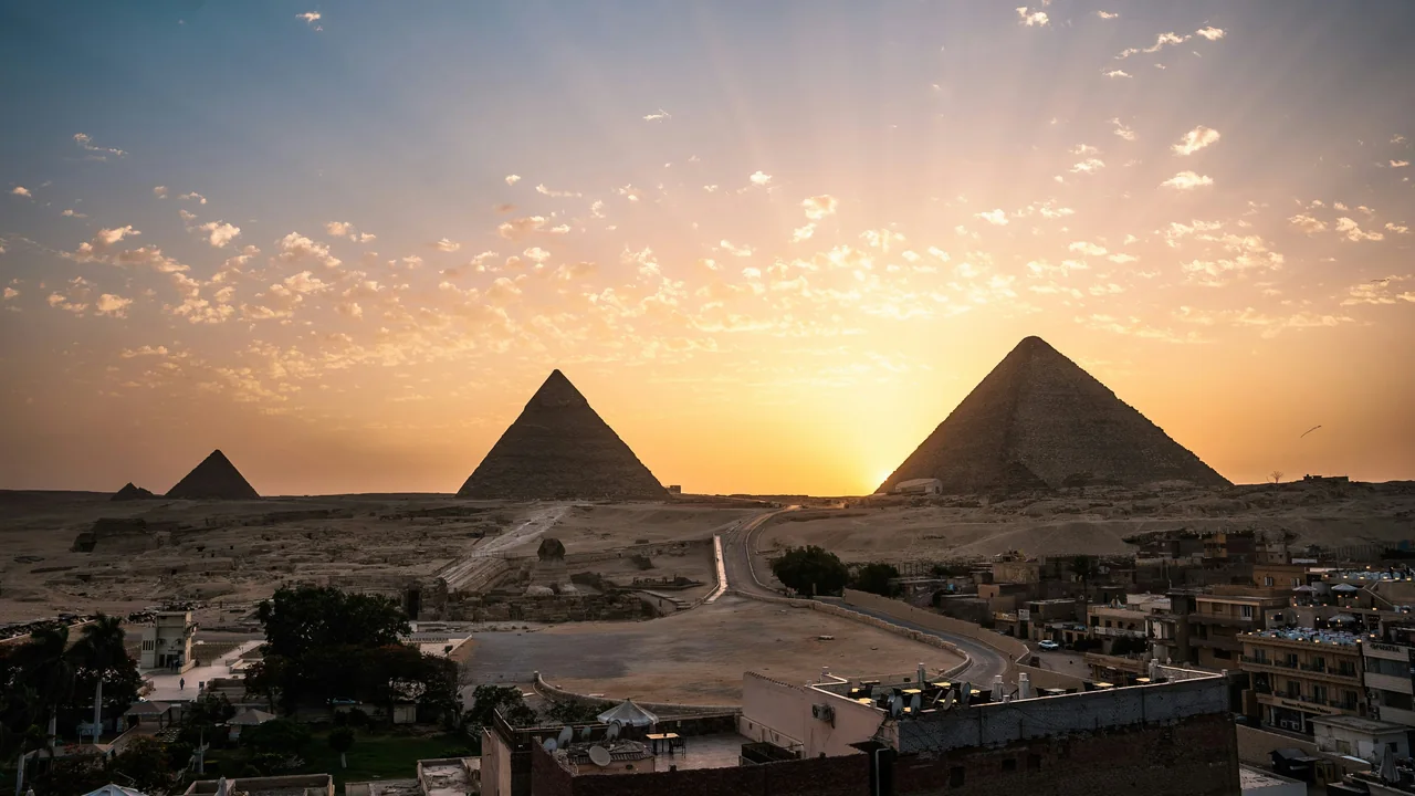 Pyramiden von Gizeh bei Sonnenaufgang hinter den Häusern der Stadt