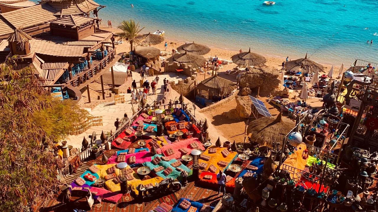 Strand mit bunten Sonnenschirmen und klarem Wasser in Sharm el Sheikh, von oben gesehen