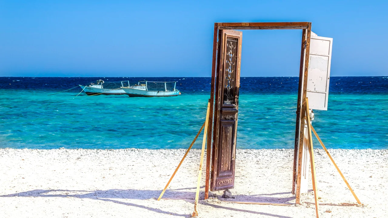 Alter Holztürrahmen an einem weißen Sandstrand bei Marsa Alam