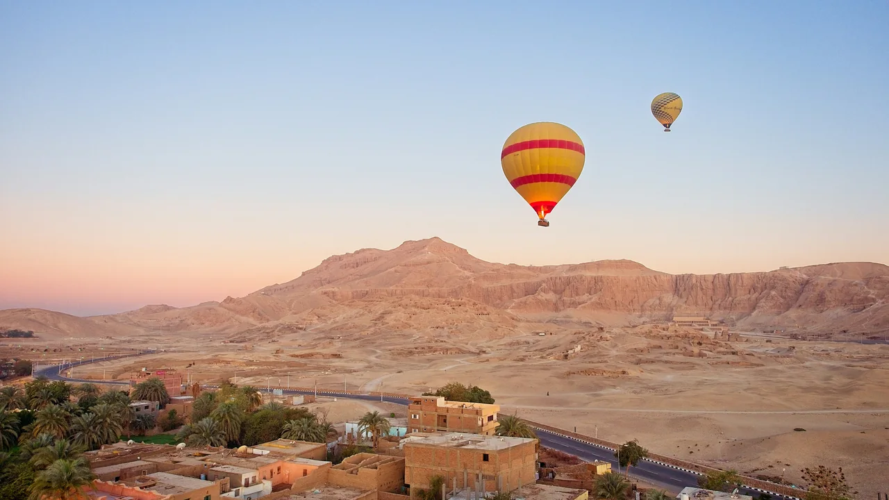 Heißluftballons über einer Wüstenlandschaft mit Häusern